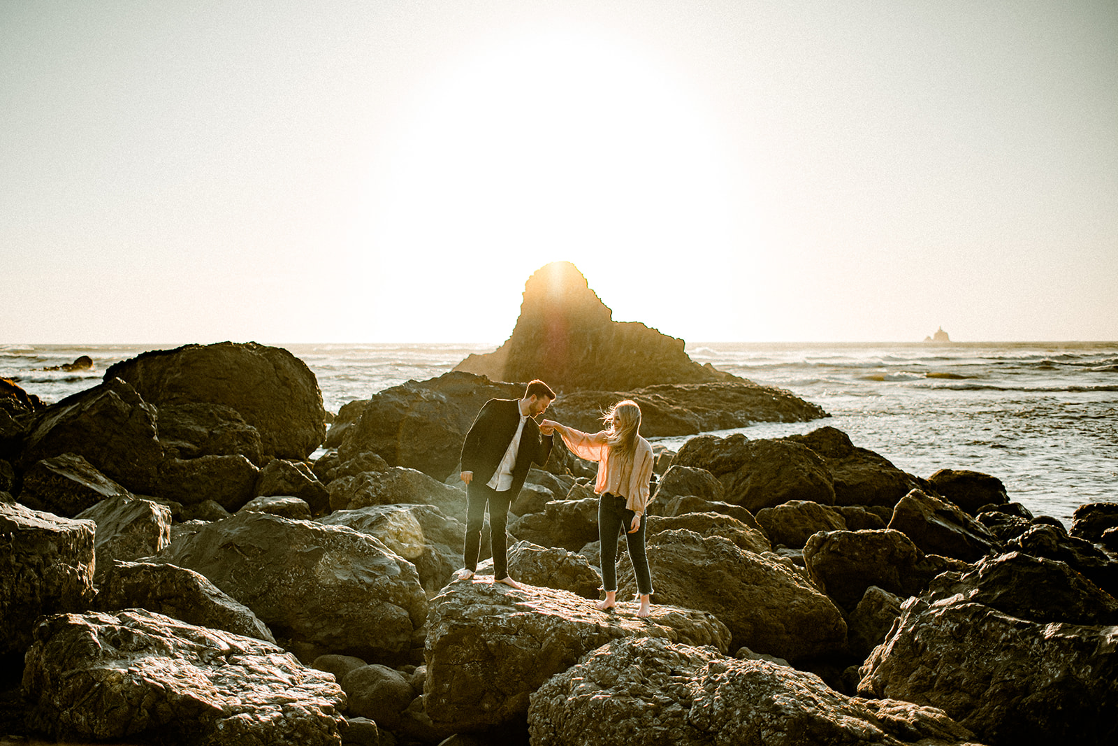 A couple posing on the jagged sea stacks at Indian Beach at their Northern Oregon Coastal Engagement