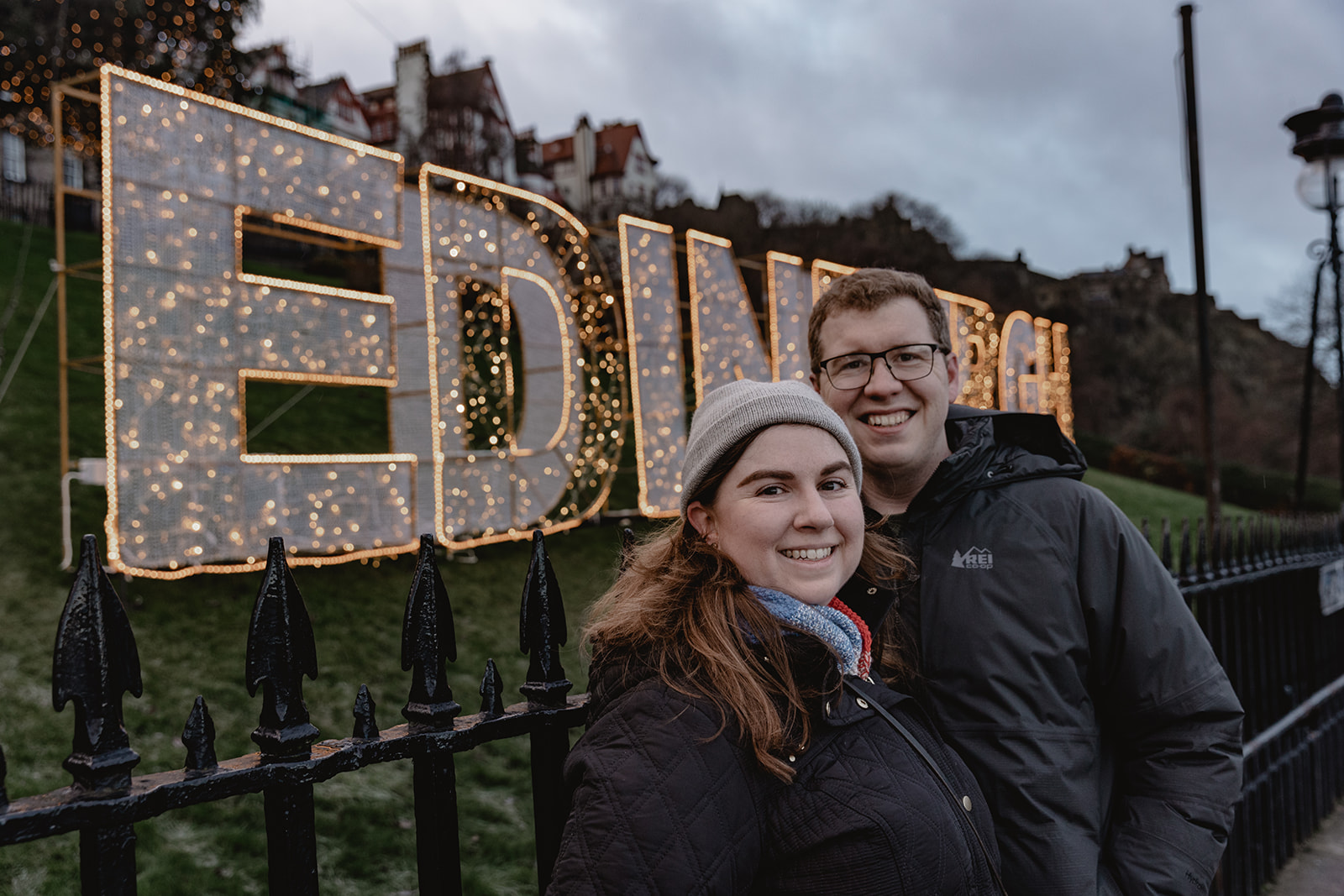 beautiful smiling couple in front of an illuminated Edinburgh sign