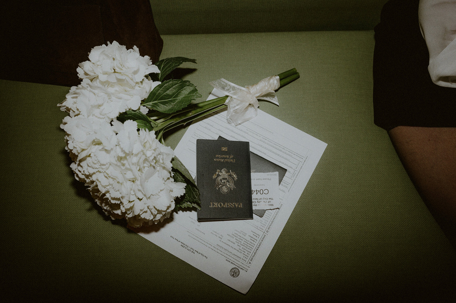 bouquet of flowers next to passport and papers on a bench at city hall