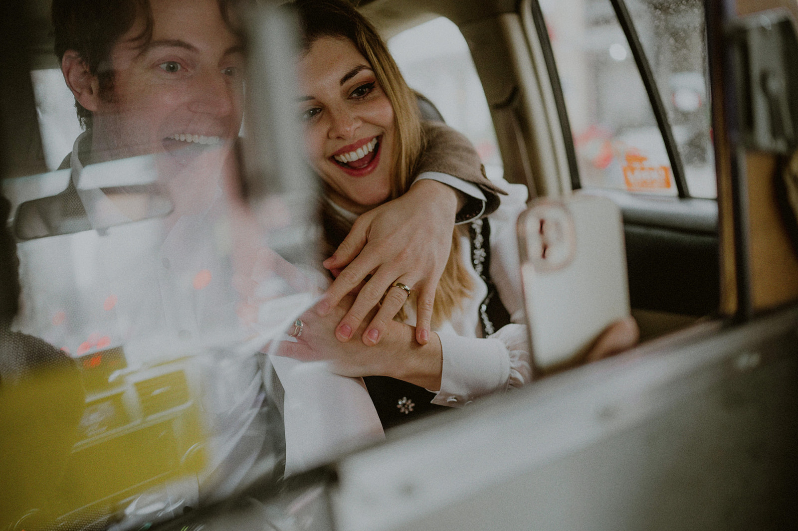 just married couple showing off their wedding ring on a phone call in the back of a nyc taxi cab