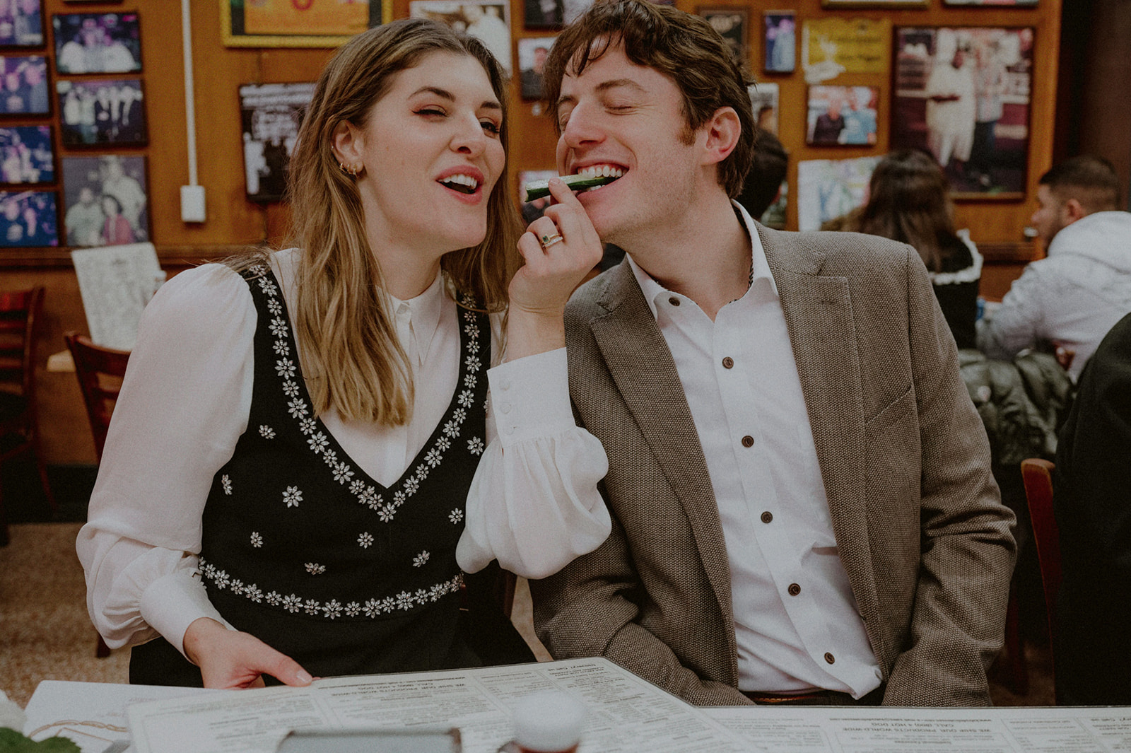 just married couple sharing a pickle at katz deli to celebrate their nyc elopement at city hall