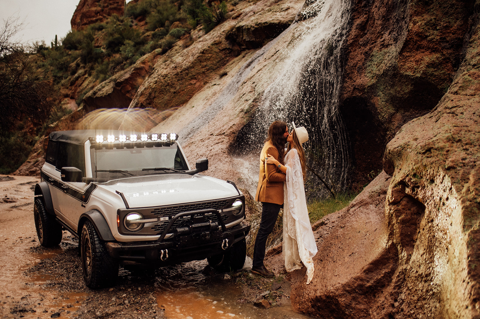 Couple kissing near their Ford Bronco and a waterfall