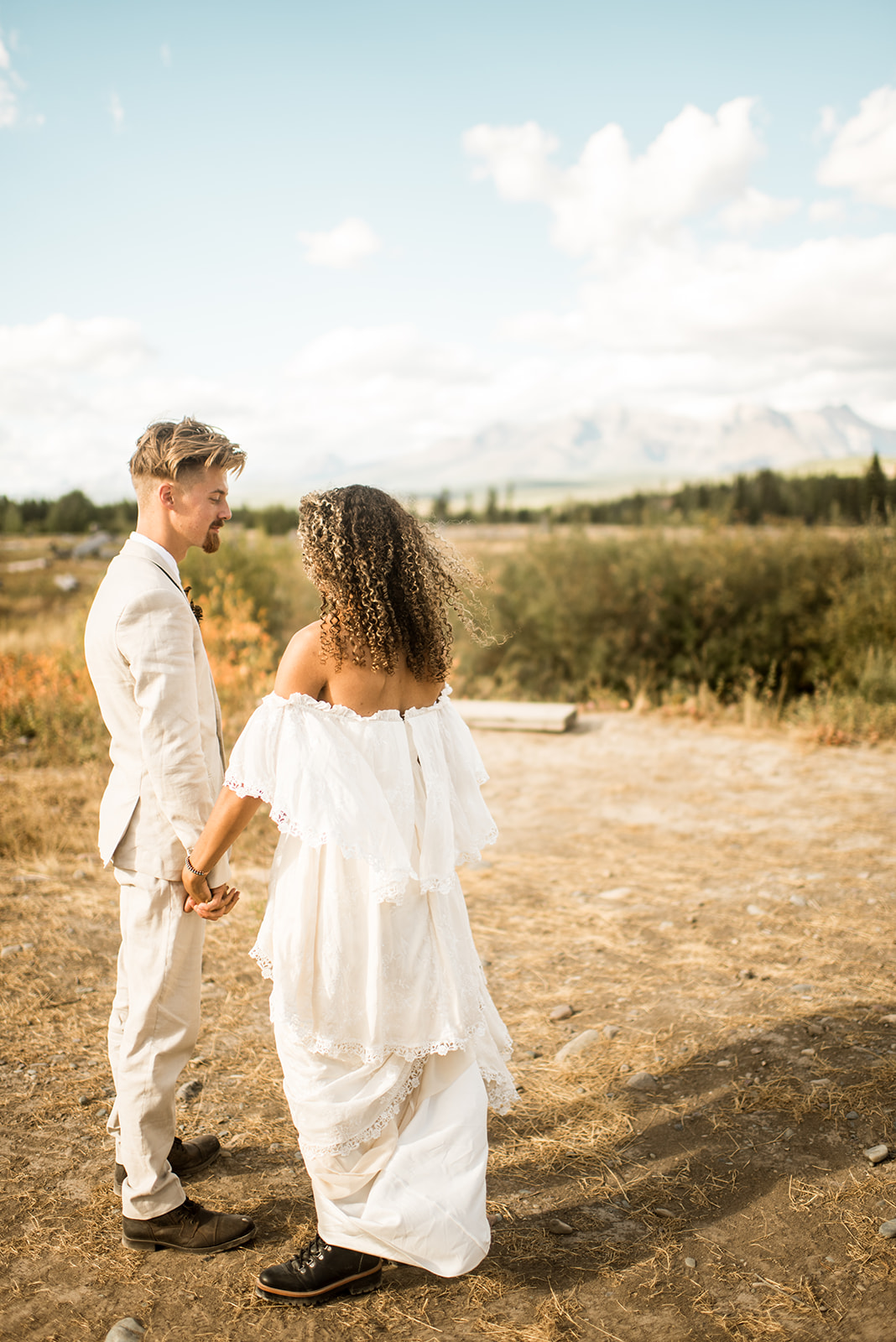 couple holds hands before their elopement in Polebridge, Montana with the mountains in the distance