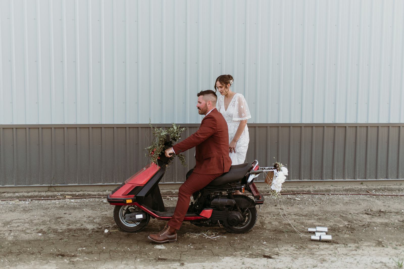 A newlywed couple with their 80's style scooter. 