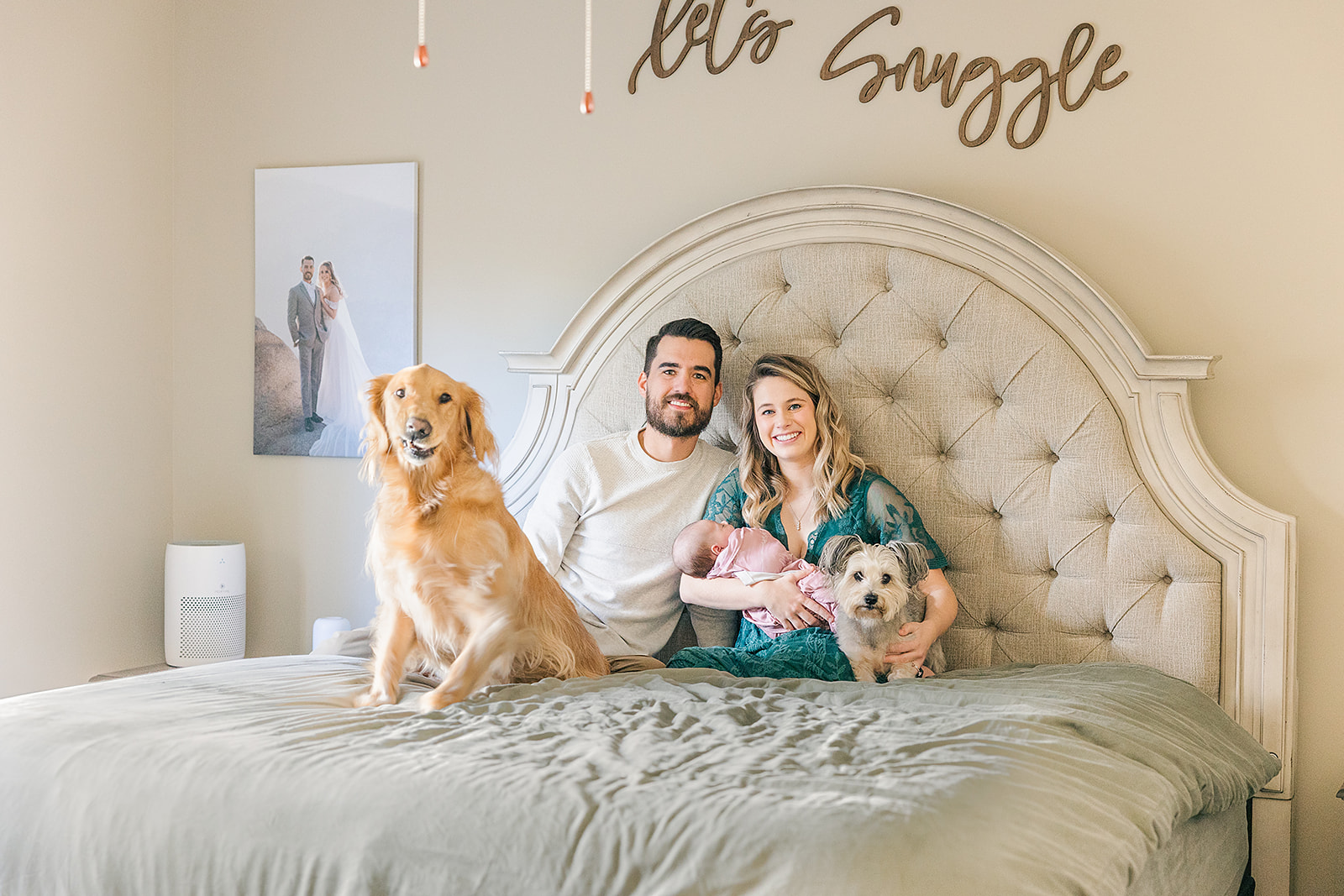 newborn parents on bed snuggling with baby girl and golden retriever dog