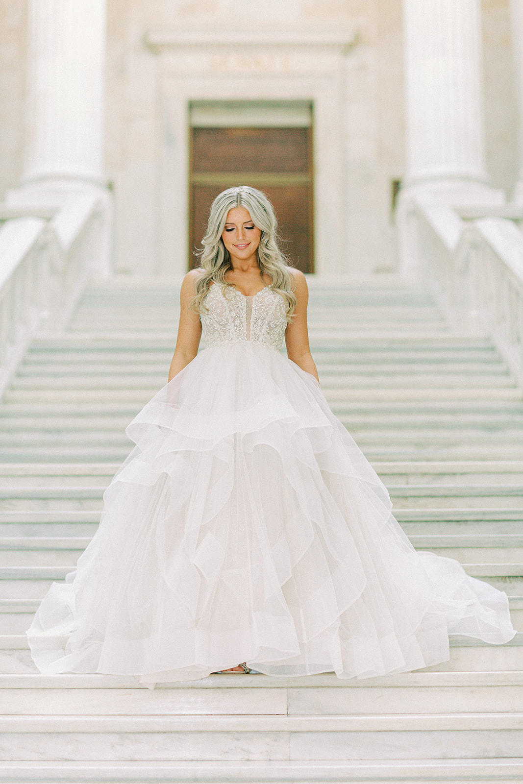 a bride walking down the stairs at the Arkansas state capitol in her wedding dress