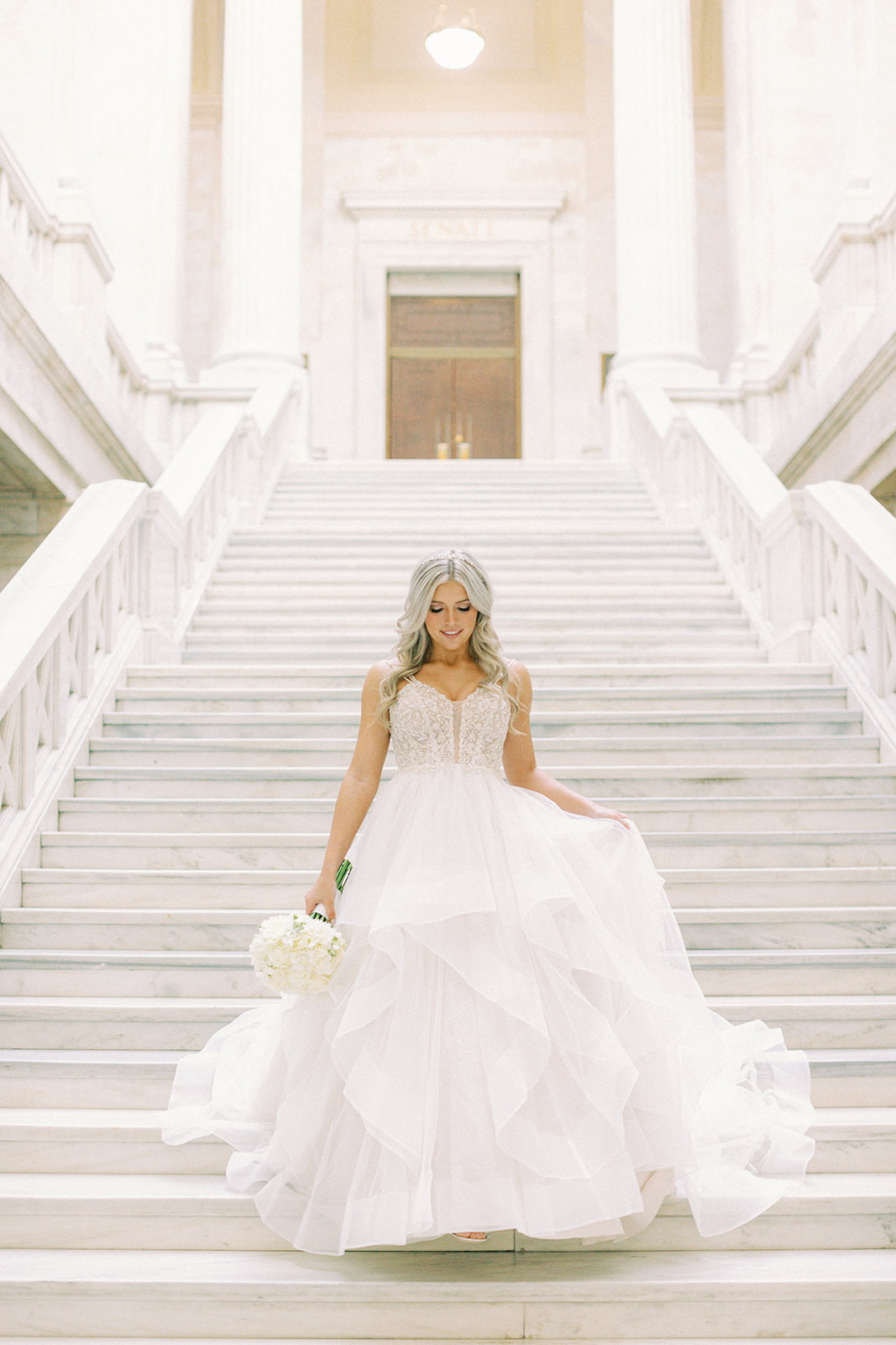a bride walking down the stairs at the Arkansas state capitol in her wedding dress