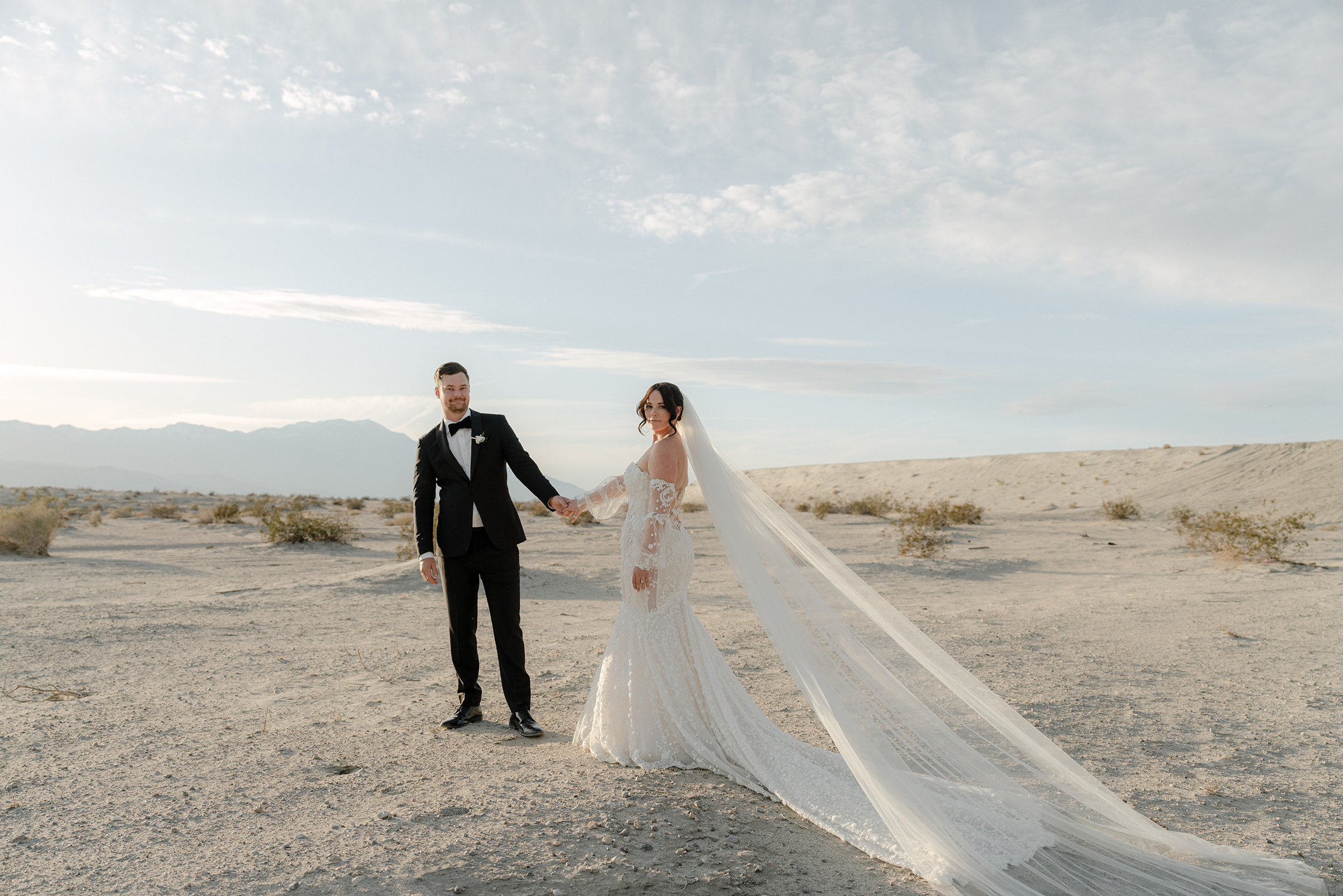 A couple who was just married hold hands in the desert