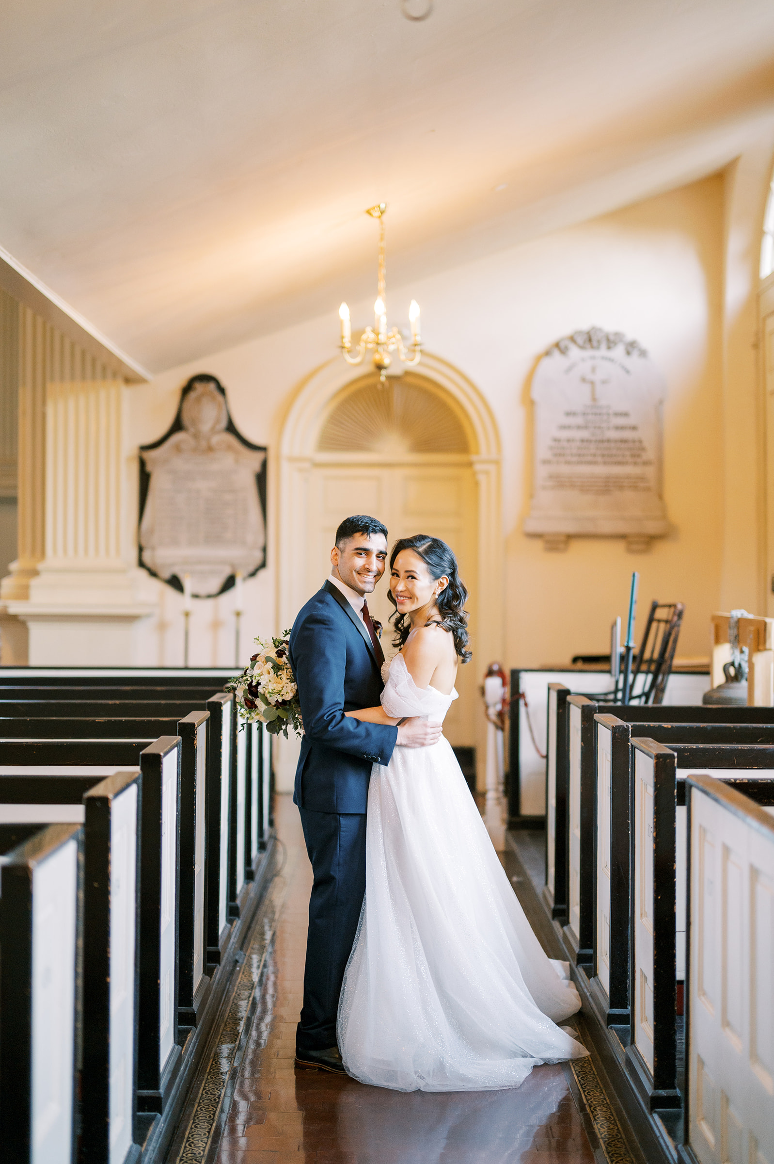 bride and groom embrace in church aisle at Christ Church in Phildadelphia for classic and airy winter wedding