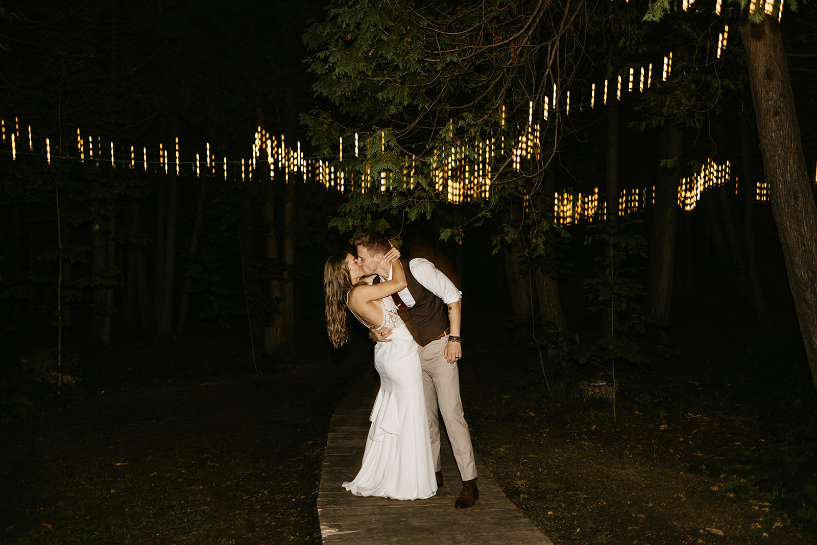 Maddie Lymburner and Chris Hartwig kiss under the fairy lights at their wedding reception