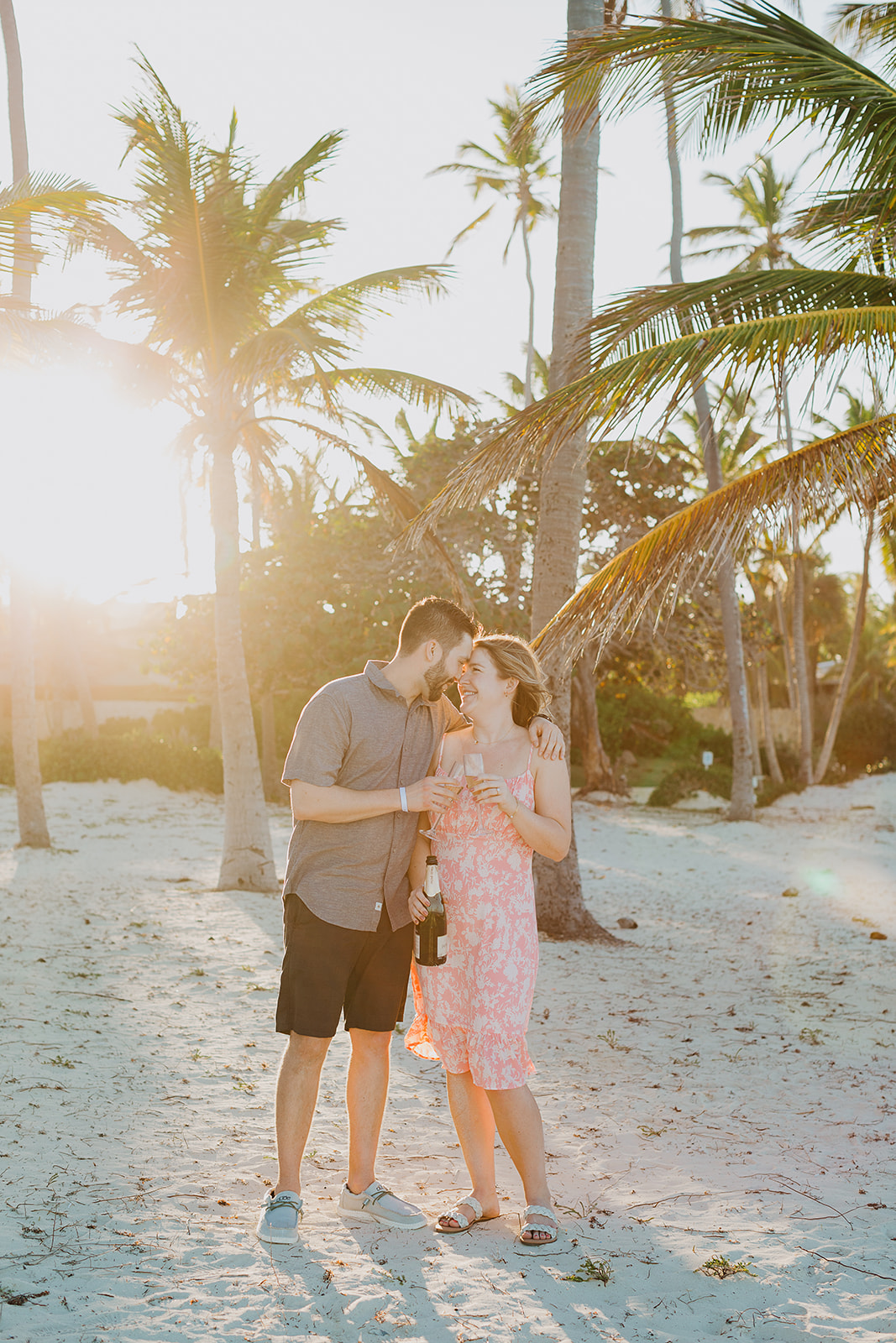 Palm trees and golden sunset behind newly engaged couple on the beach in Punta Cana