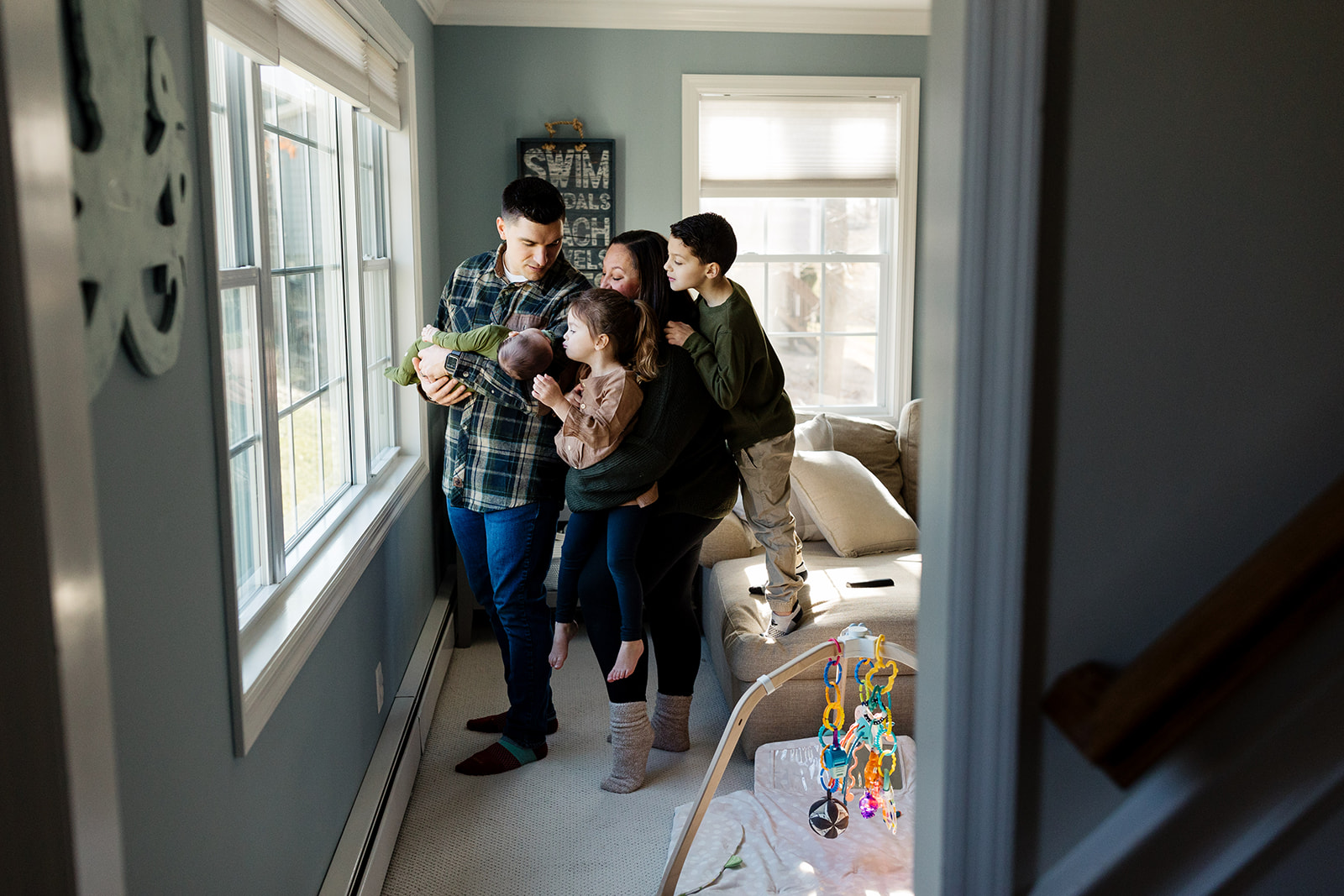 A family surrounds the newborn brother during a during their family photo session at home.
