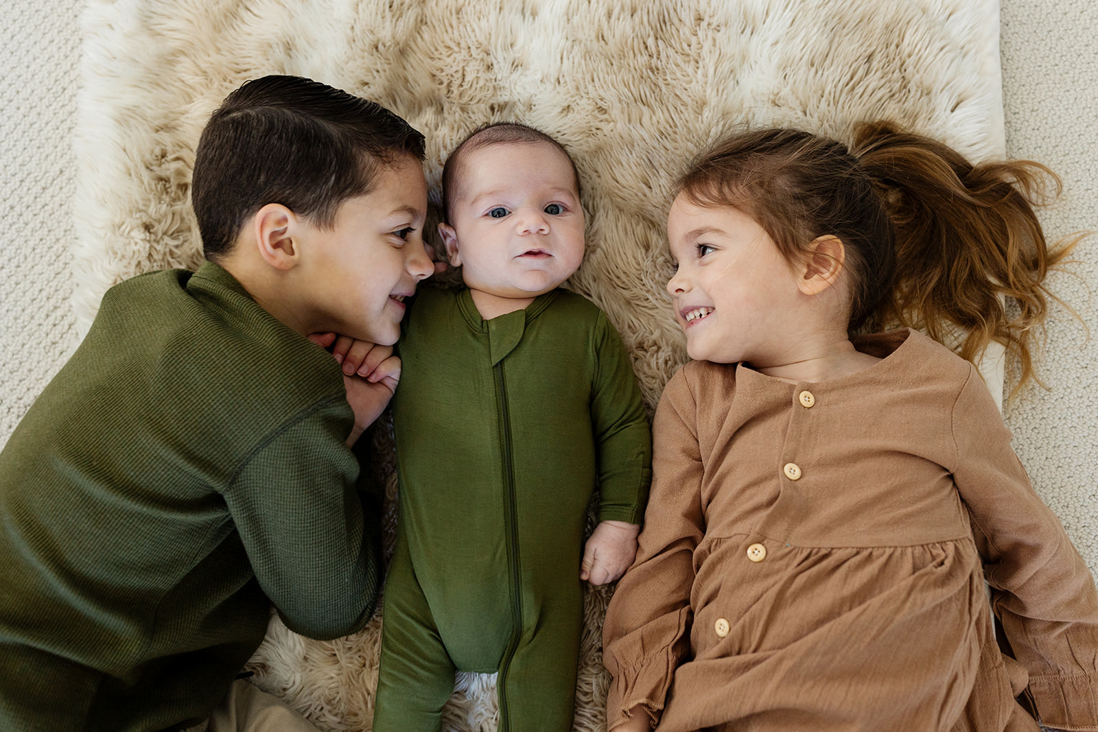 A brother and a sister look at their newborn brother during their family photo session