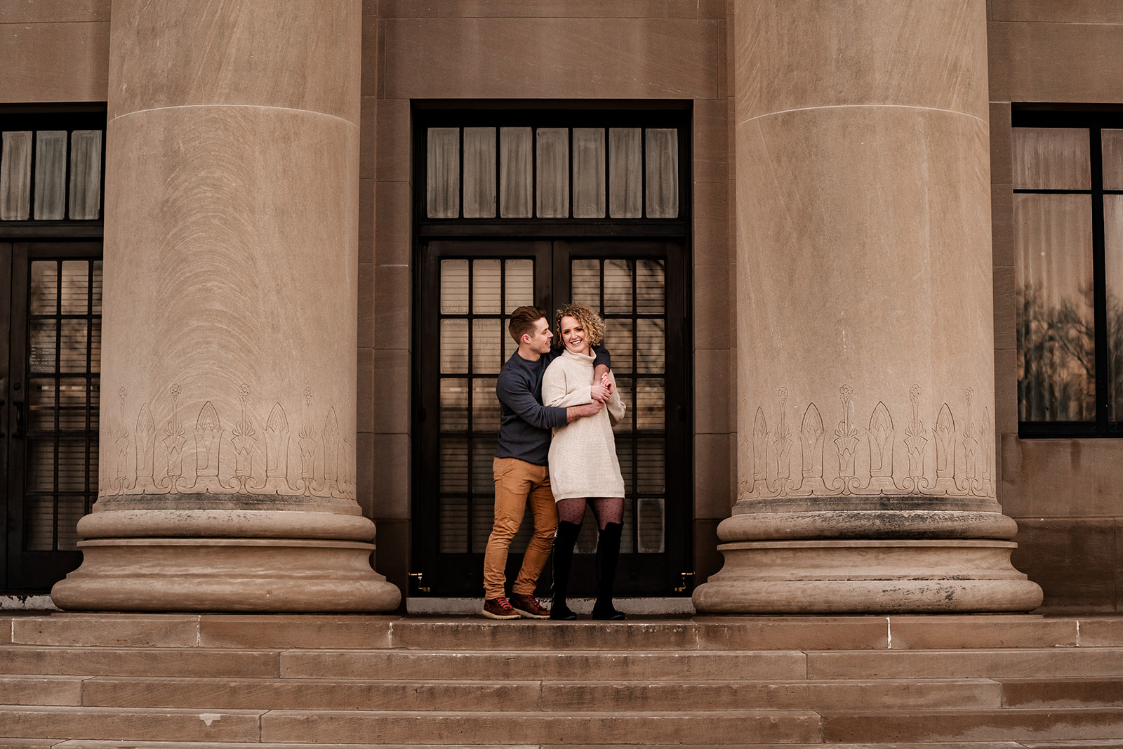 A couple standing on stairs at the Nelson Atkins Museum for an engagement session