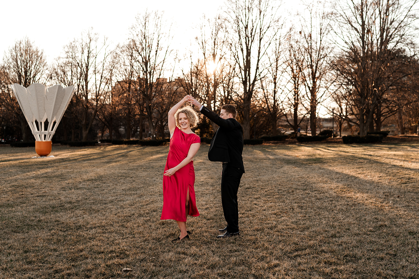 A couple twirling in front of the shuttlecock at Nelson Atkins Museum for an engagement photo shoot