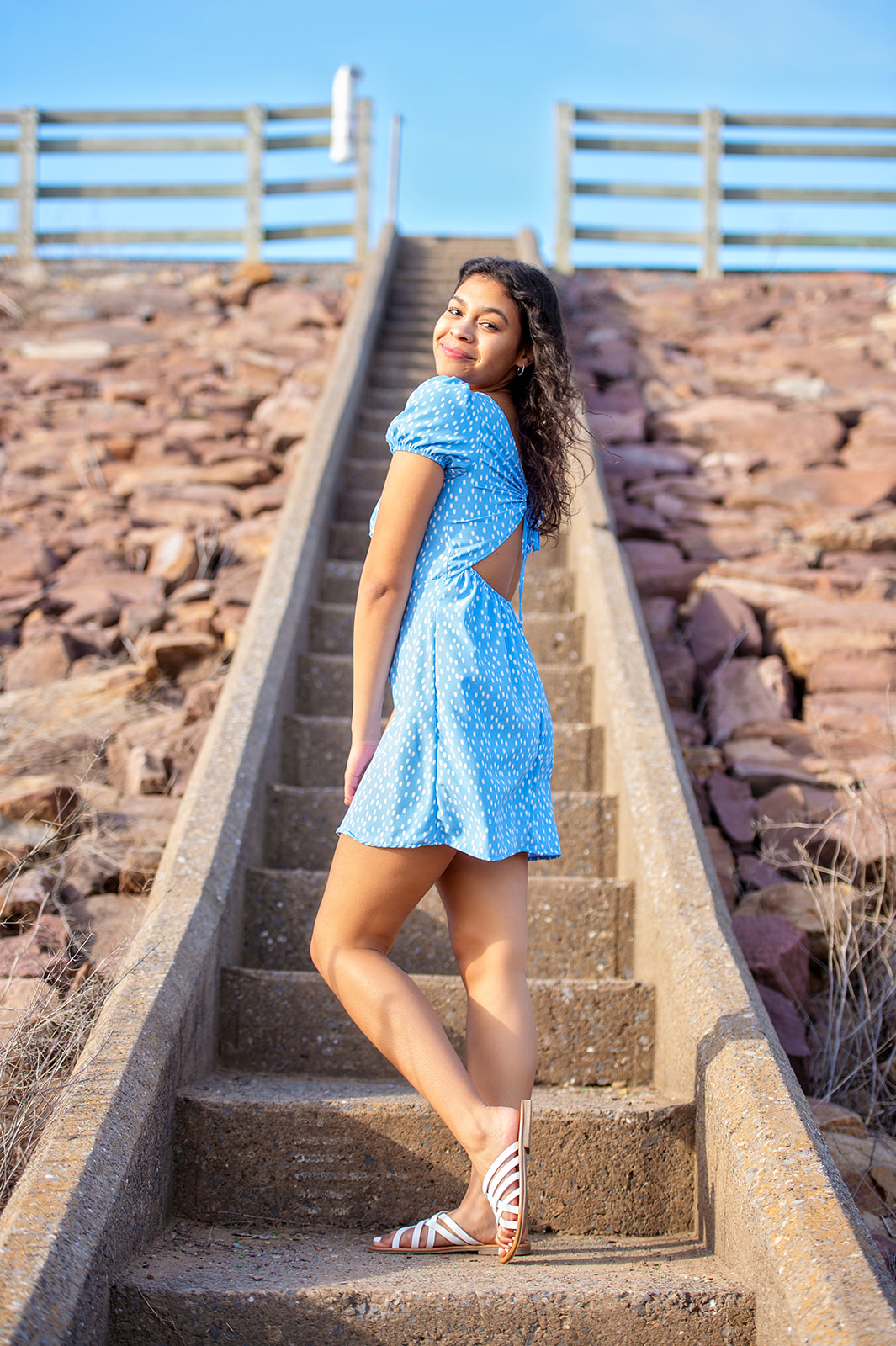 High school senior girl photos in blue dress on steps Susquehanna River. 