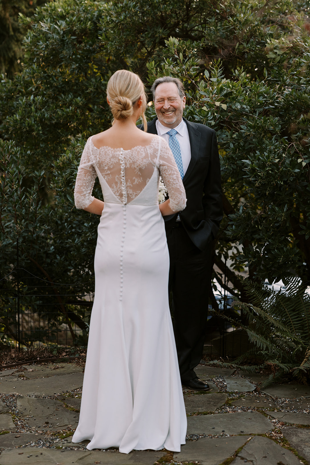 bride in lace dress walks up to older man for father and daughter first look