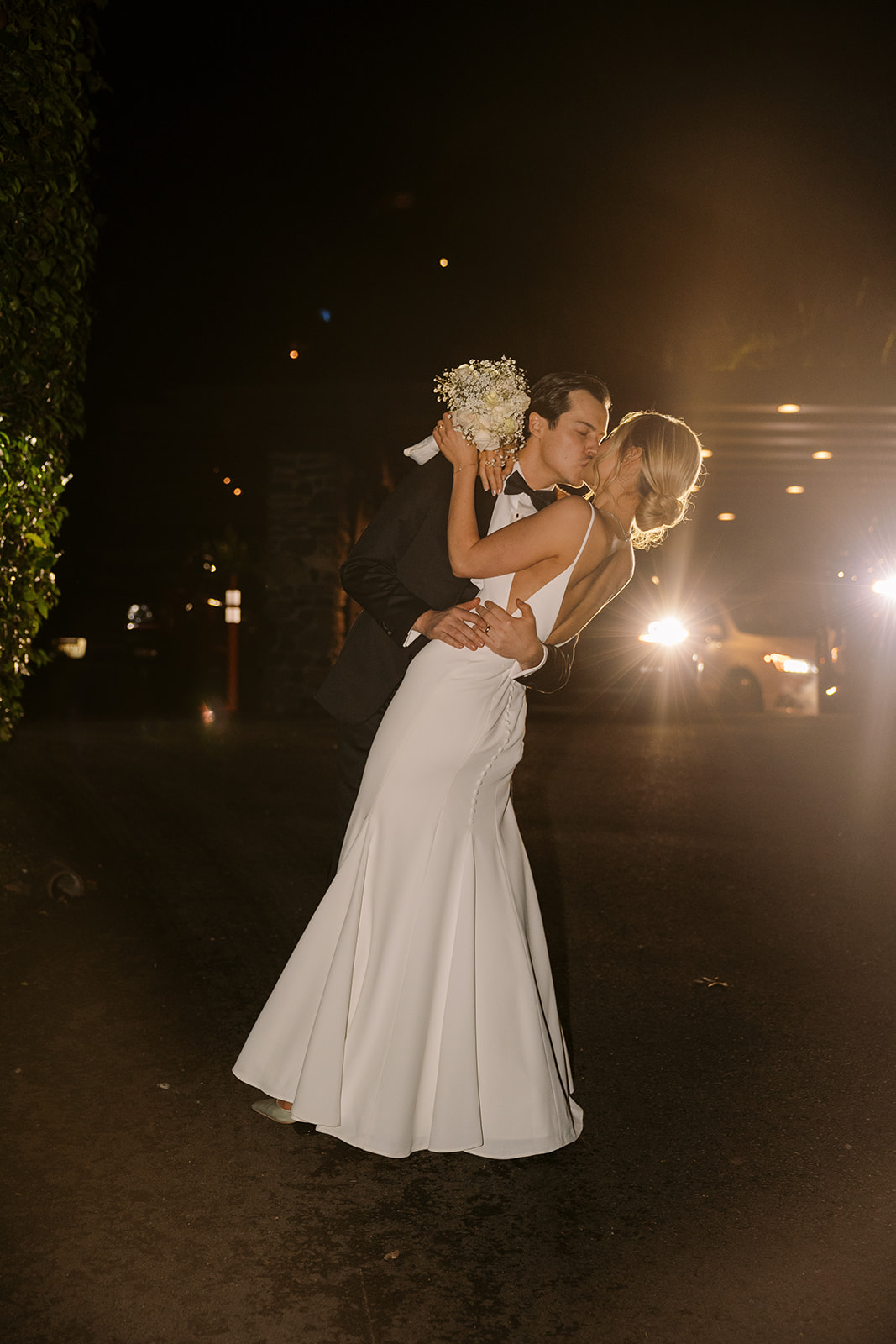 bride and groom pose in front of car lights at Canlis wedding