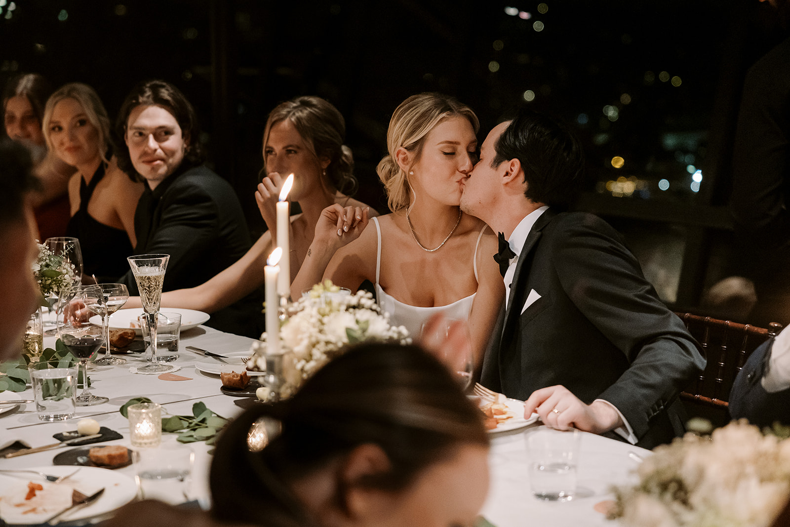 bride and groom kiss at candle lit table scape during Canlis wedding reception