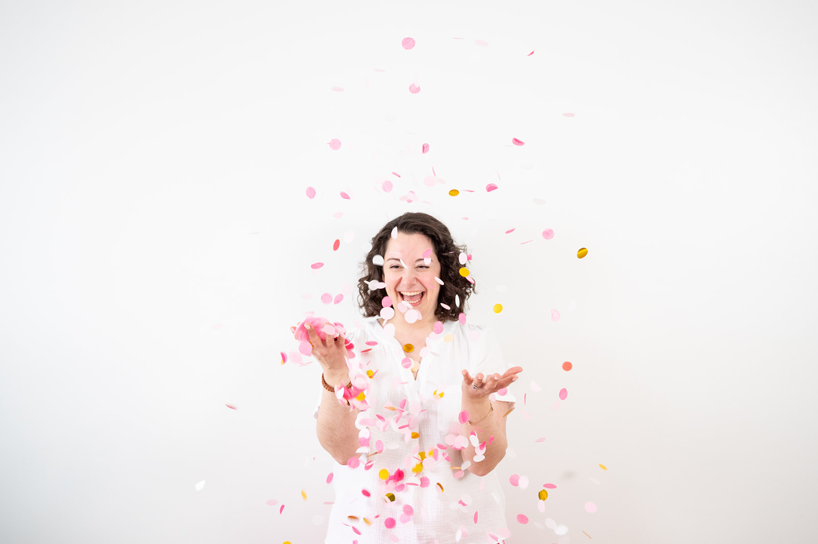 Woman throwing pink confetti and laughing on her natural Ottawa lifestyle brand photo shoot