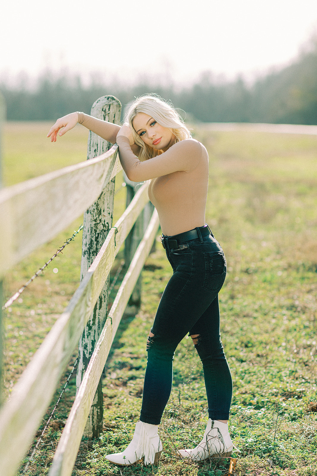 A girl in Texarkana poses in front of a fence for her senior photo session