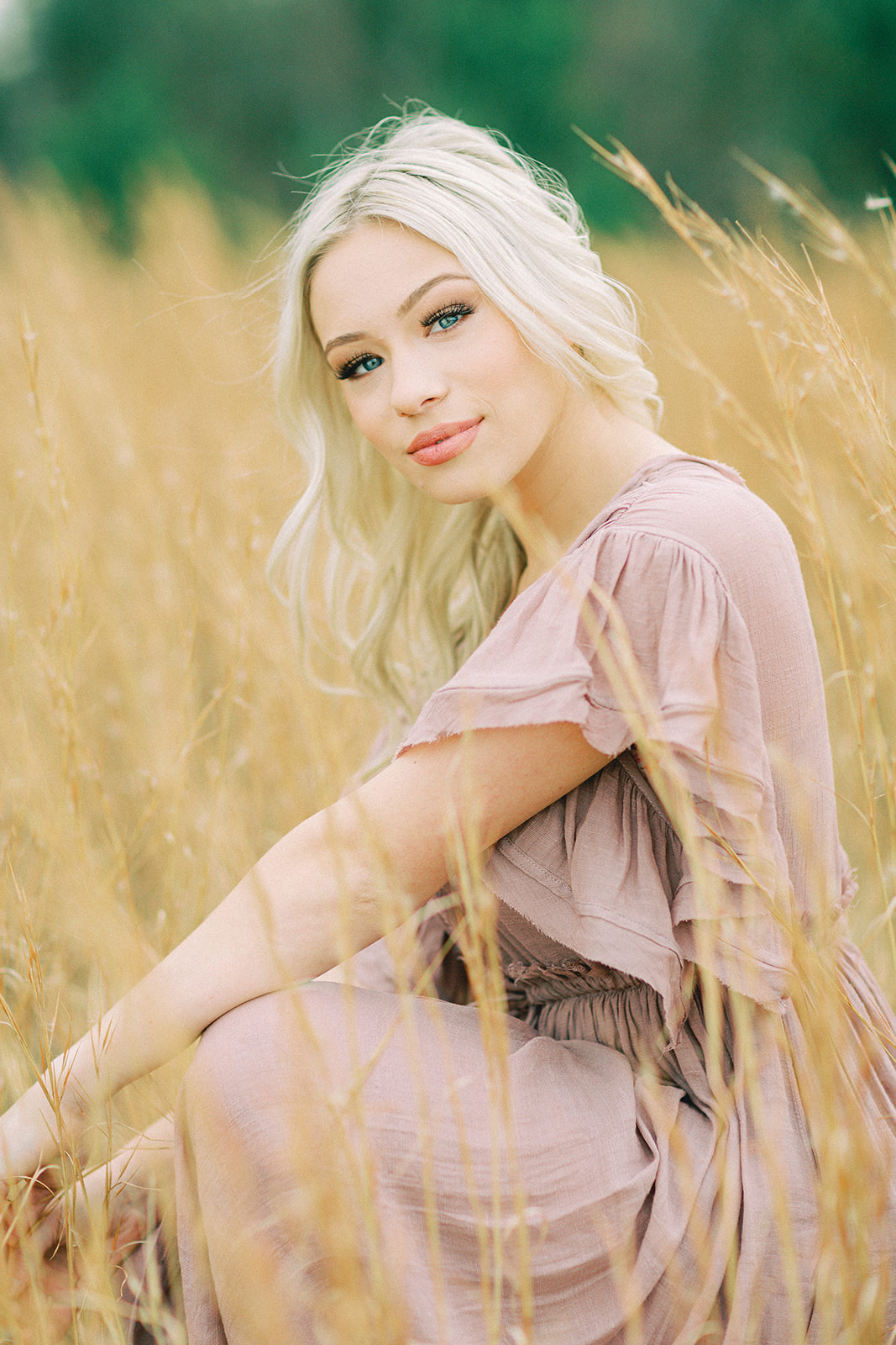 A senior girl poses in front of a wheat field for her senior session with Jessica Vickers Photography