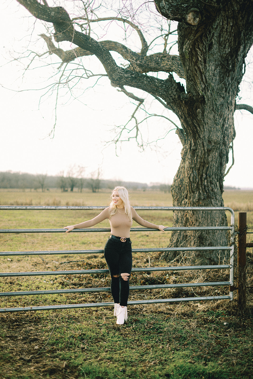 A senior girl in Texarkana poses in front of a tree and fence in Texarkana, Texas