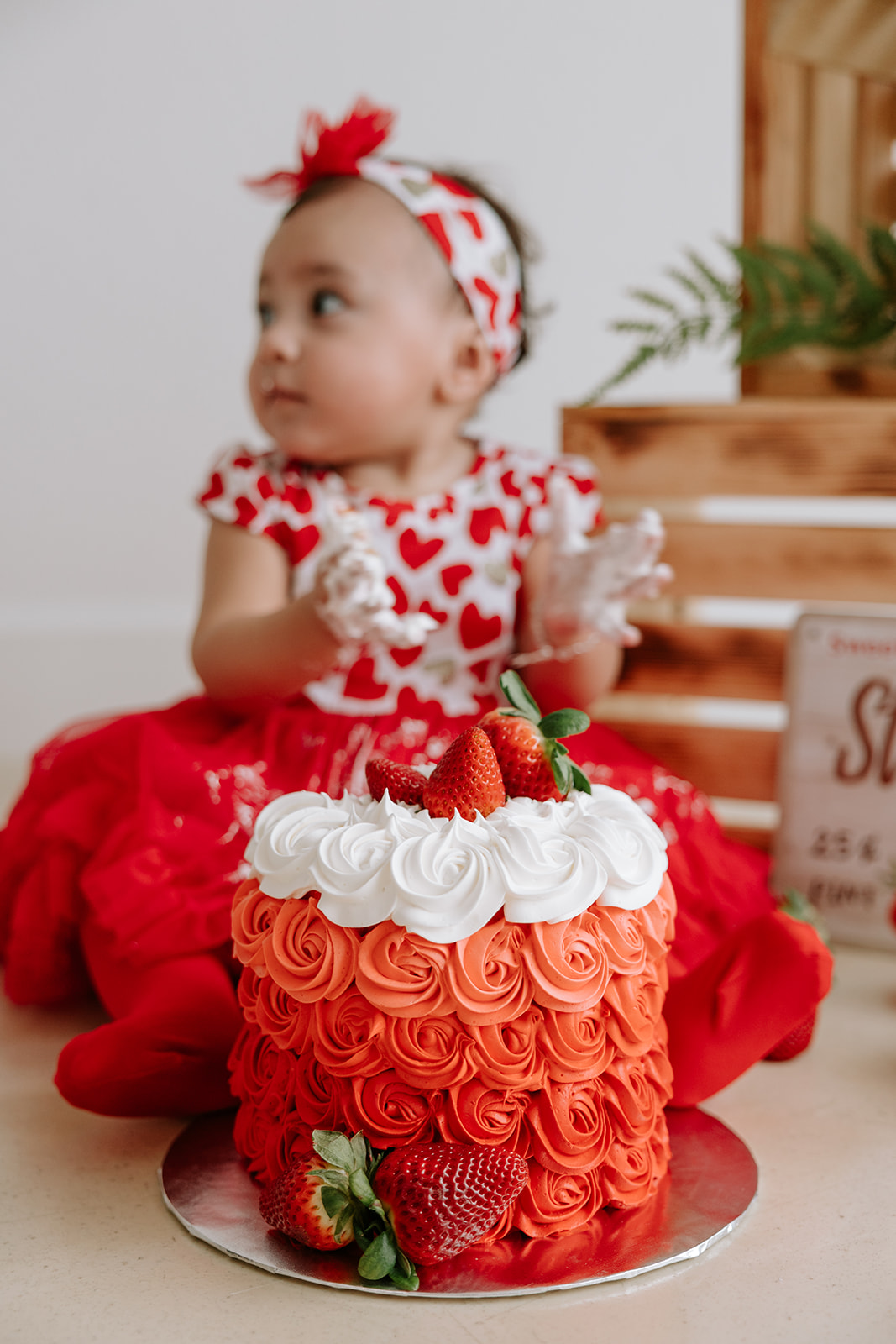 Strawberry-themed first birthday baby cake smash photoshoot.