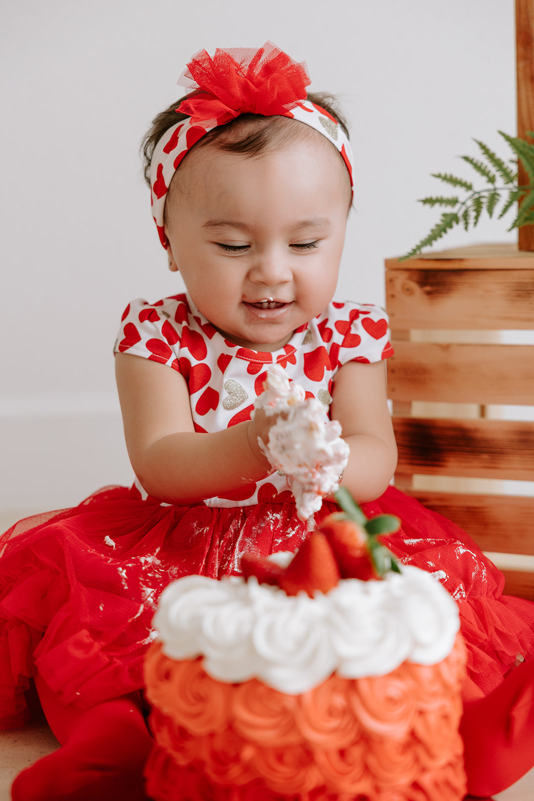 Strawberry-themed first birthday baby cake smash photoshoot.