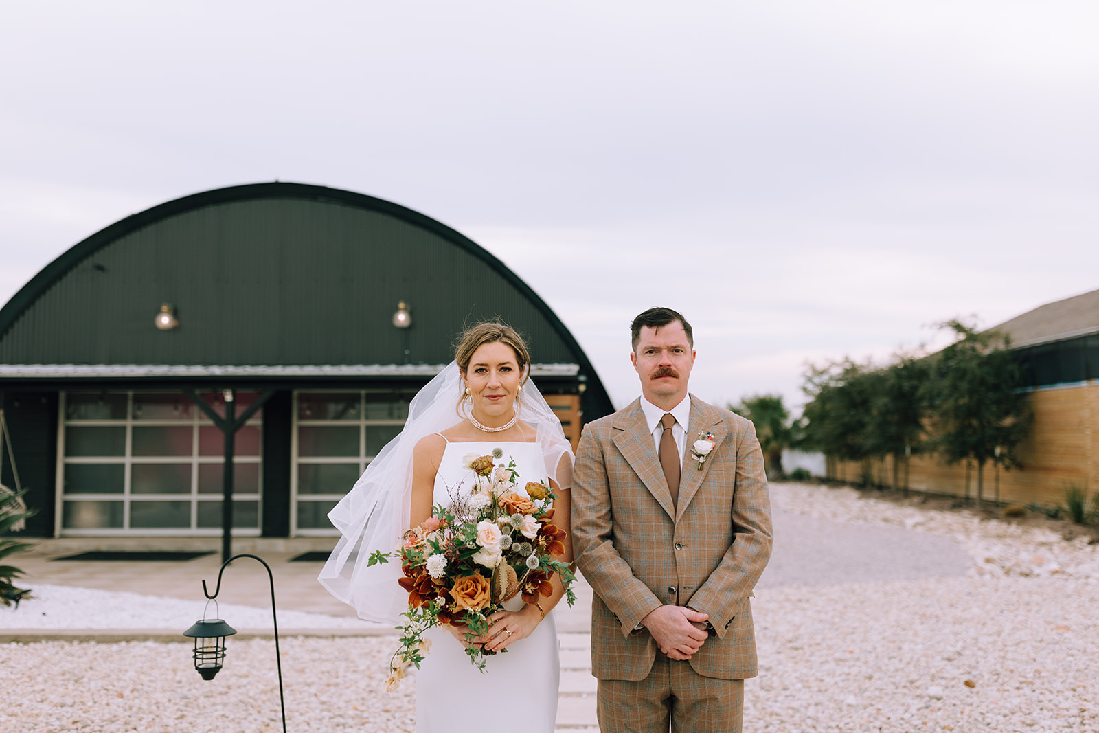 couple stands side by side at outdoor wedding venue