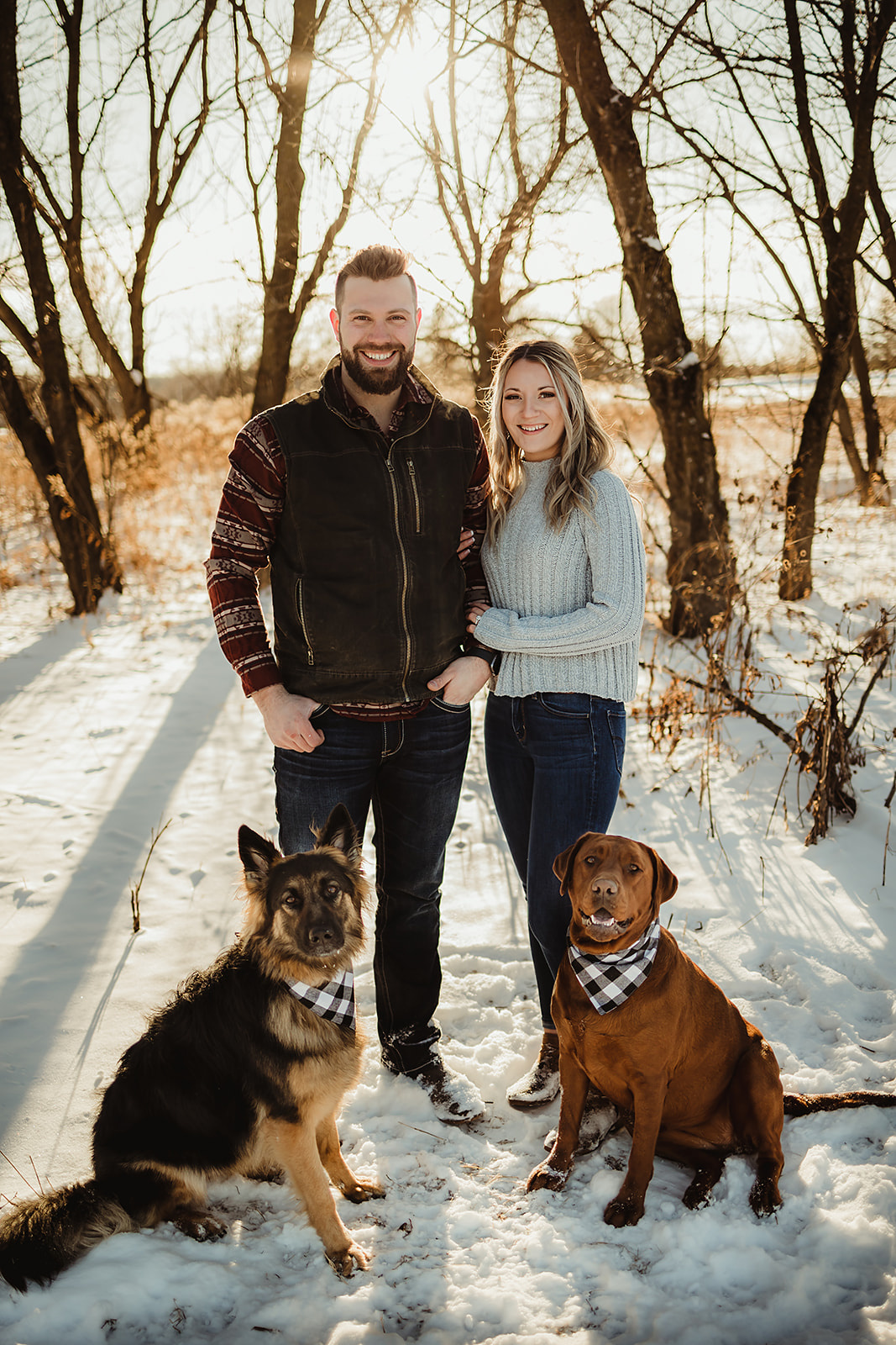 A couple in love take engagement pictures with their dogs in a Cozy park in Green Bay Wisconsin