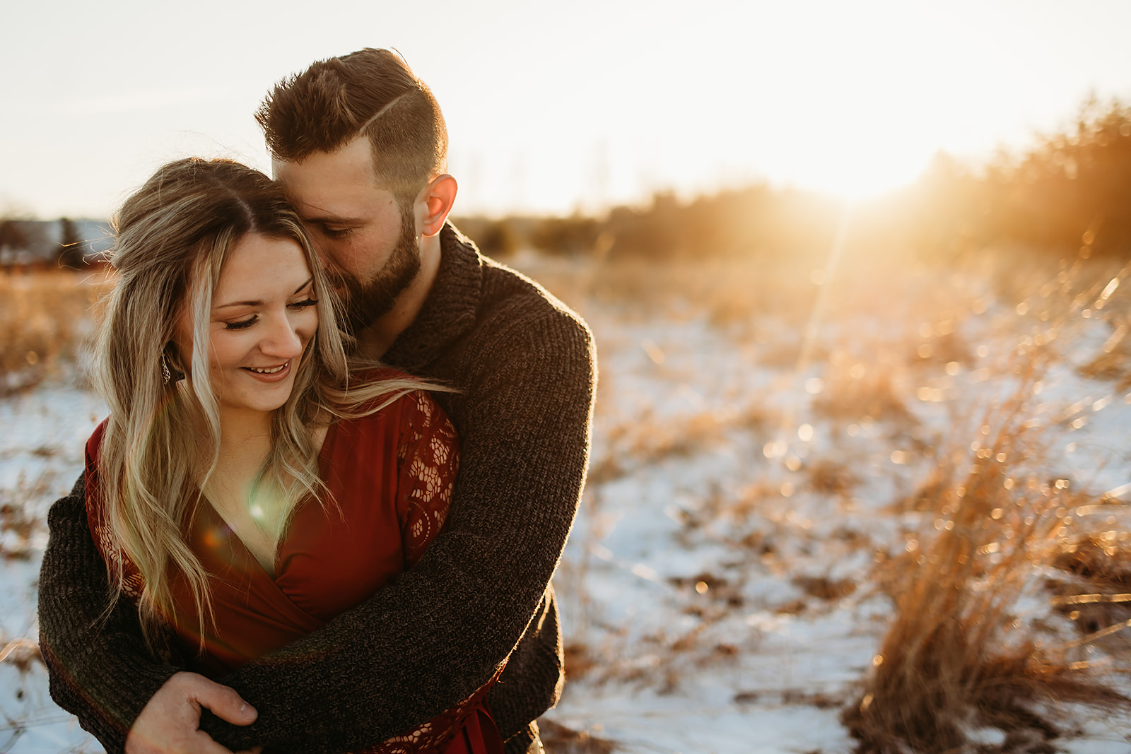 A couple in love take engagement pictures with a beautiful sunset in a Cozy field in Green Bay Wisconsin