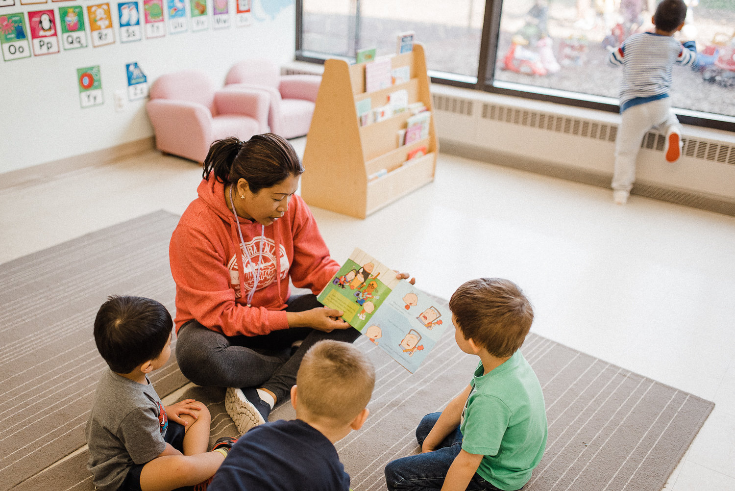 A daycare teacher reading a book for kids