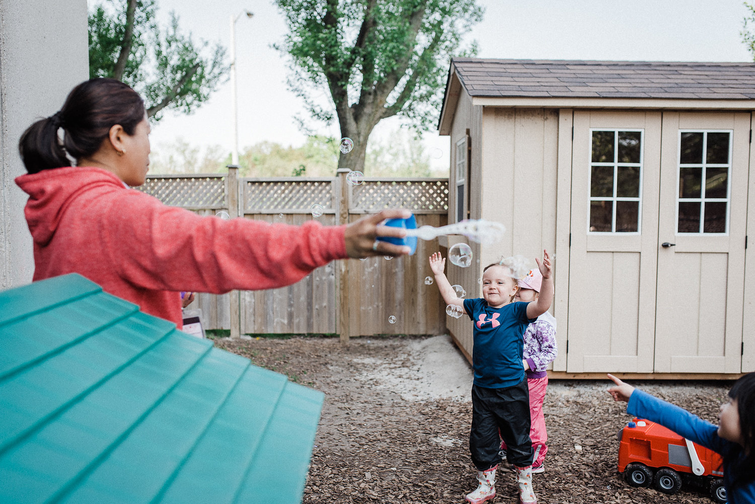 A daycare teacher is making bubble for children in the backyard