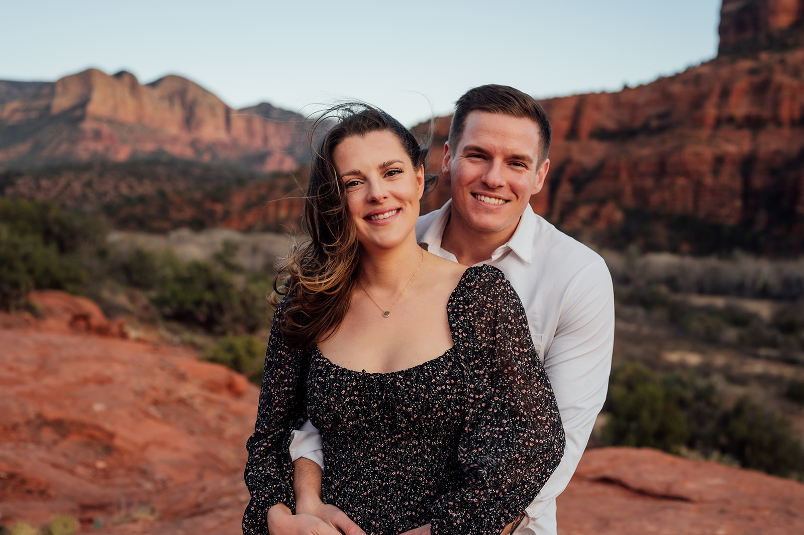 couple cuddling in front of the Red Rocks of Sedona, AZ
