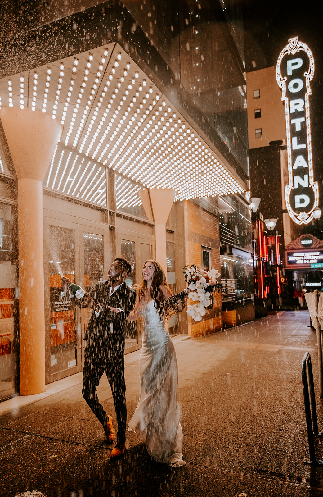 Bride and groom  Popping champagne at the Arlene Schnitzer Hall during their nighttime elopement in downtown portland