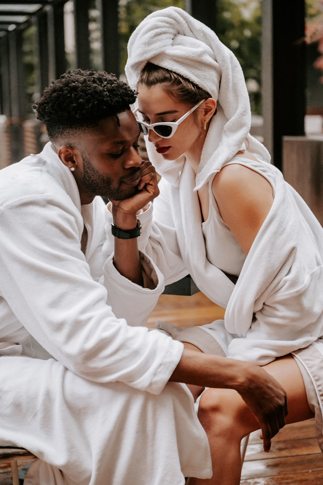 Couple embracing at hotel zags in downtown portland. Wearing robes and she has a towel on her head and white sunglasses