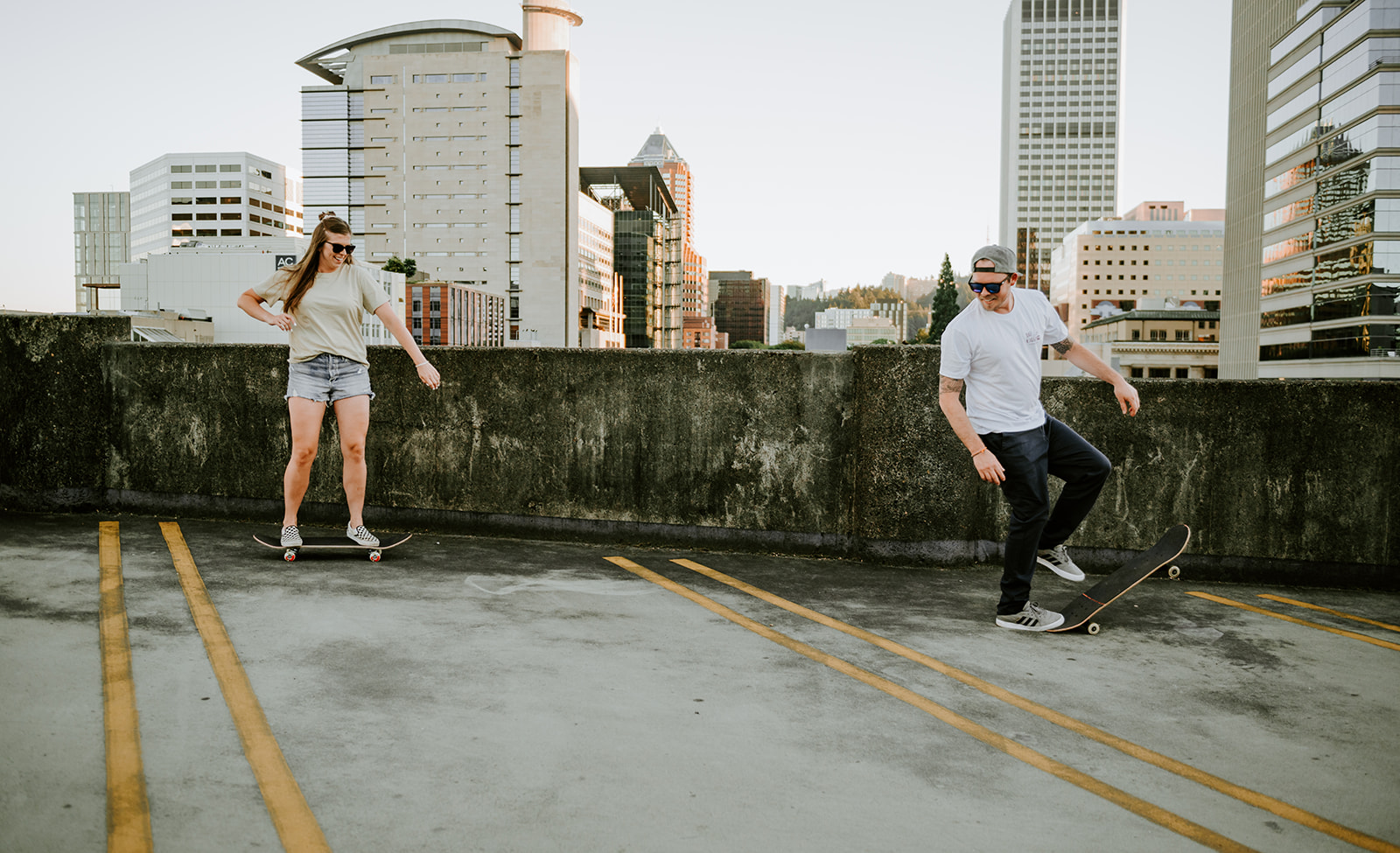 A couple skateboarding together during their engagement session in a parking garage in portland