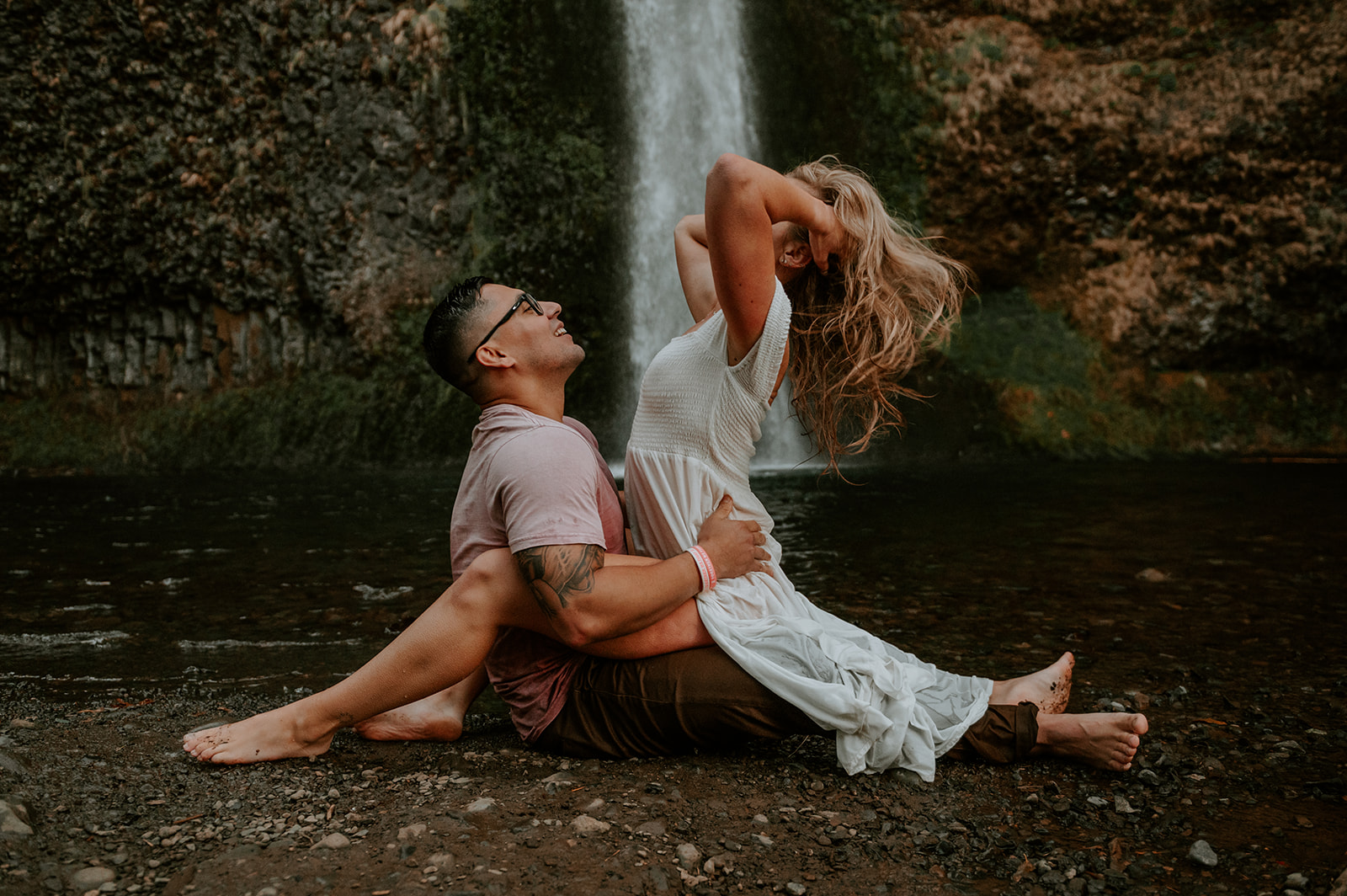 Couple playing at the base of horsetail falls. Girl is start telling the guy and playing with her hair
