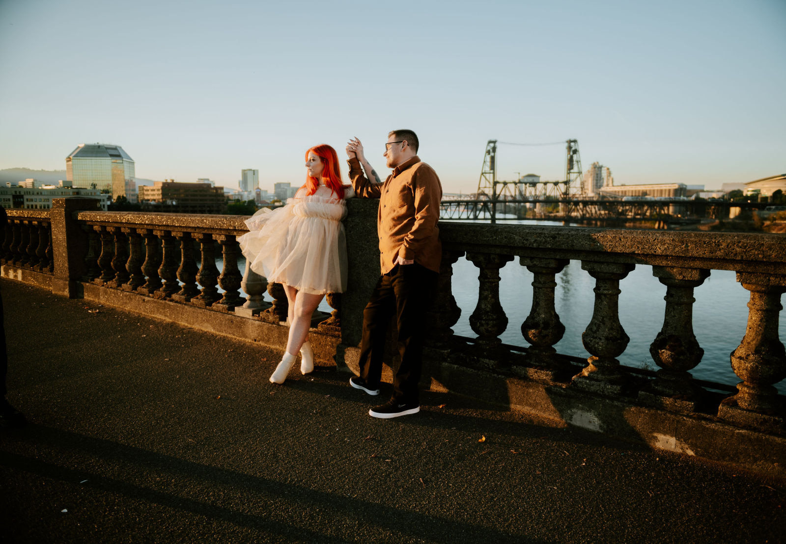 Couple holding hands on the burnside bridge in Portland Oregon with the steel bridge in the background