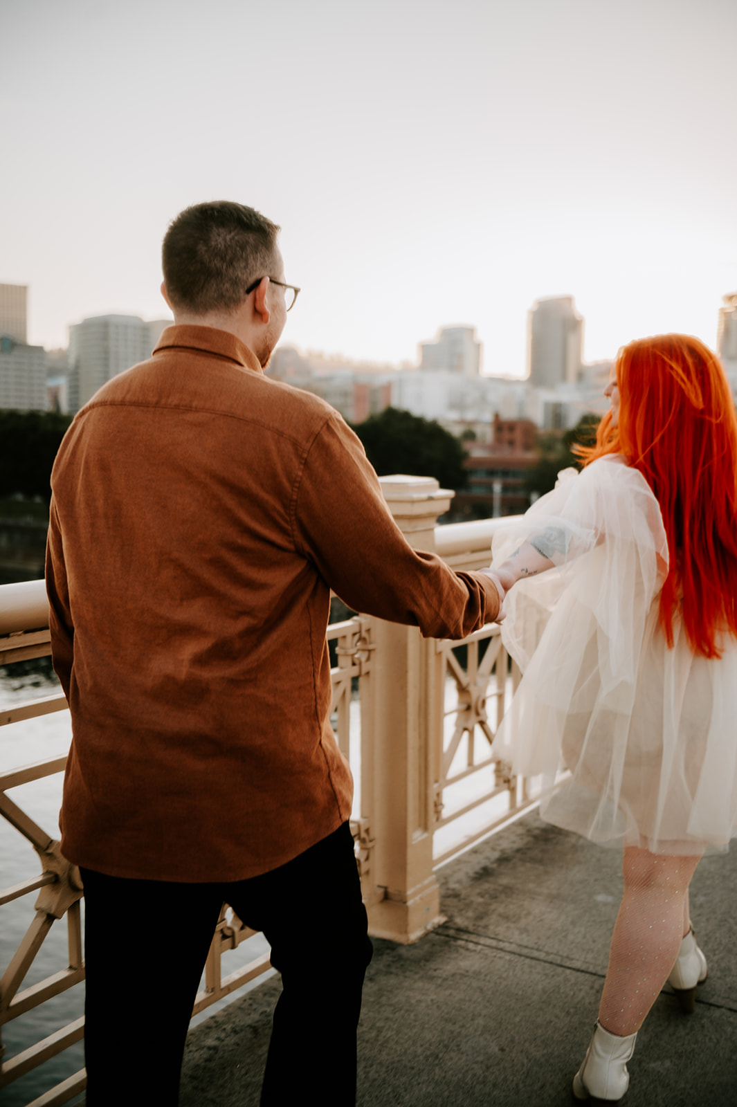 Couple walking on burnside bridge in Portland with downtown in the background