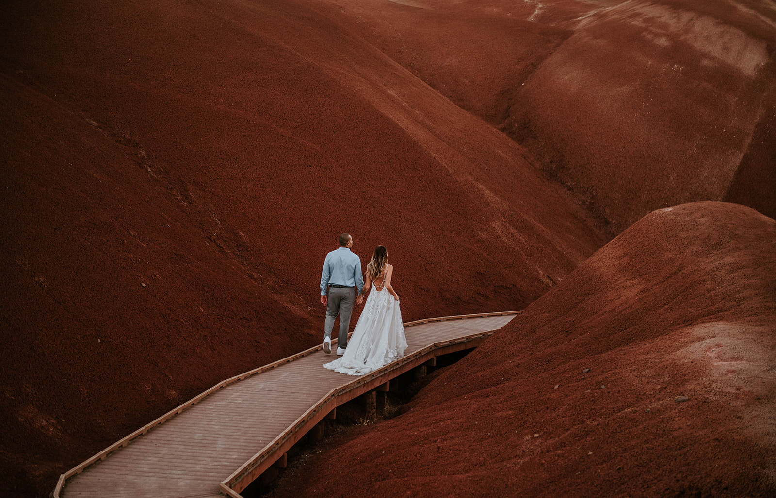 A couple who eloped walking on the bride in the red hills at the Painted HIlls