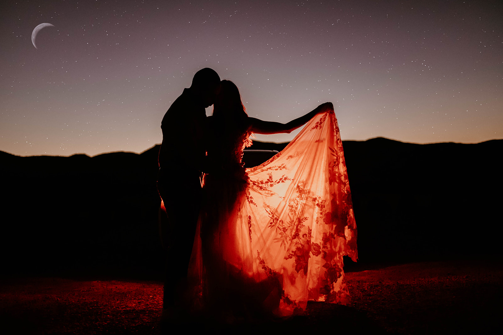 A couple standing under the starry sky with the dress lit up red
