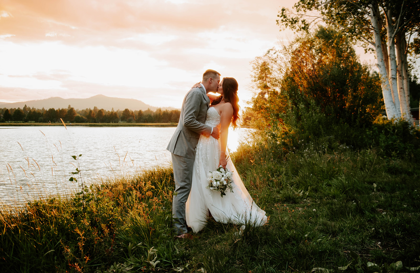 Bride and groom kissing at sunset on the lake at black butte ranch 