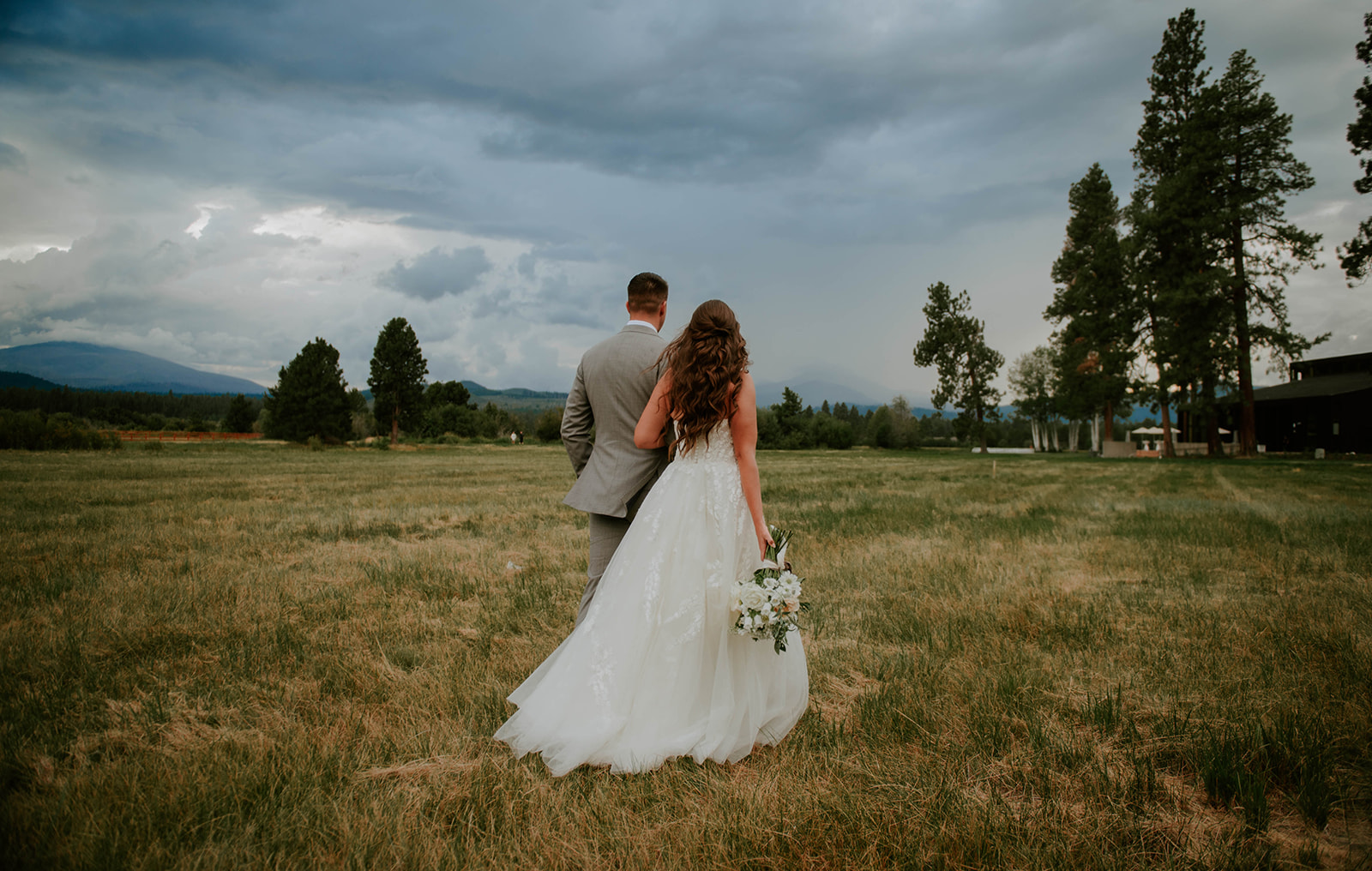 Bride and groom walking into storm clouds at black butte ranch