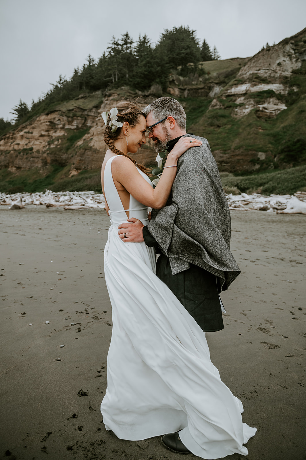 Bride and groom embracing in the wind on the Oregon coast