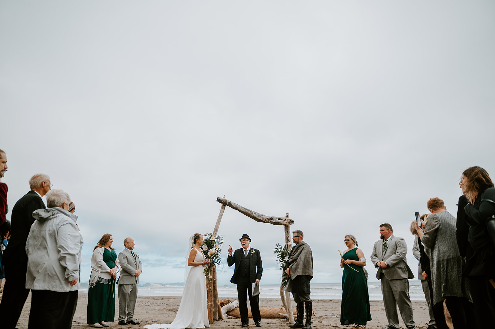 Bride and groom kissing under DIY driftwood altar on the Oregon coast 