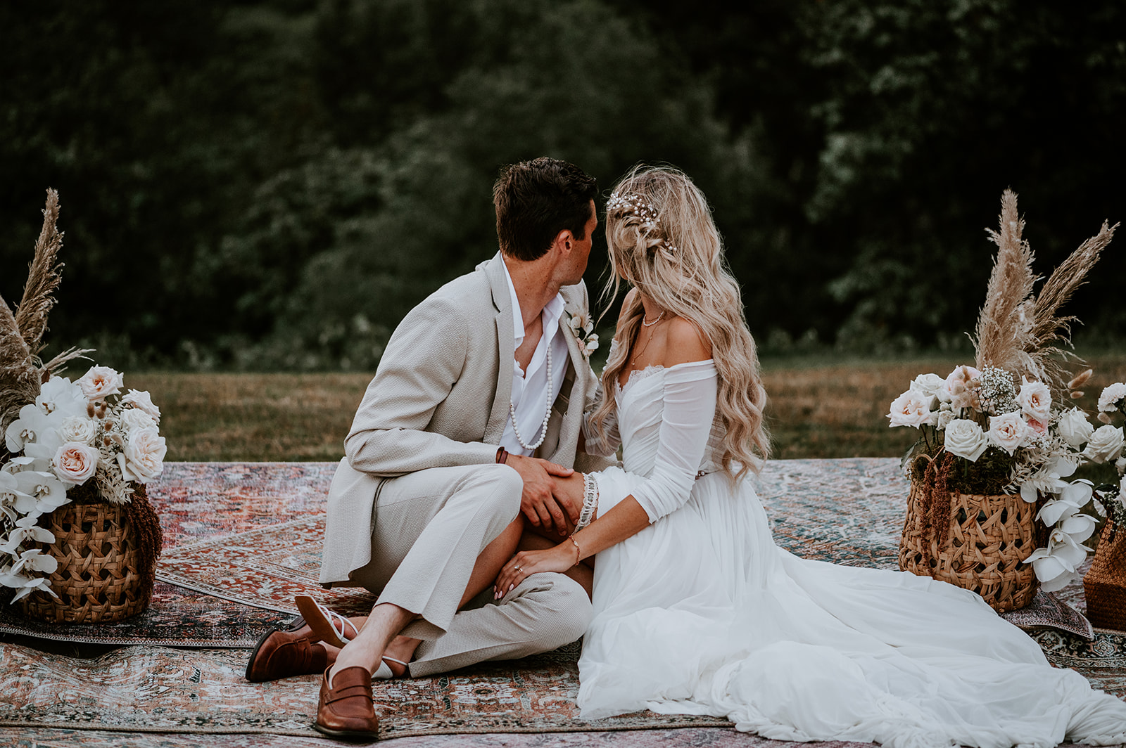 Bride and groom sitting on a boho rug looking over their shoulders