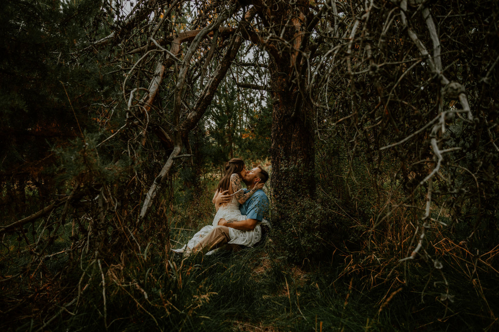 Bride straddling groom and making out in the trees at Dillon falls 