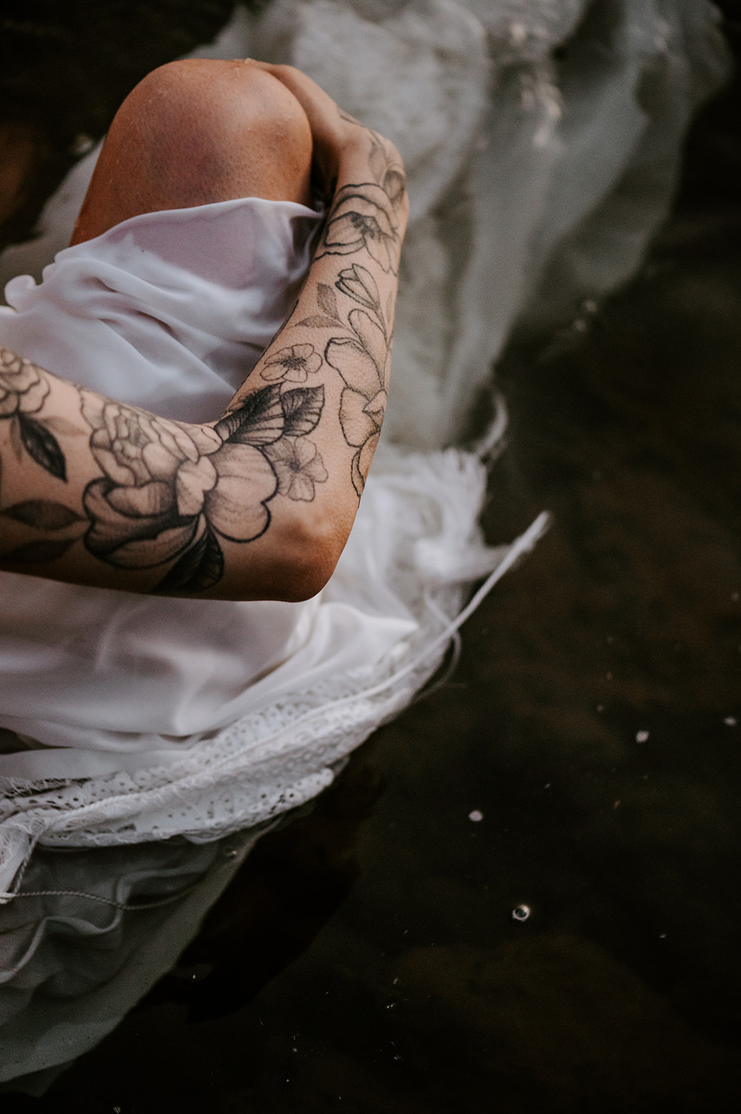 Close up of Bride with tattoos sitting in the water